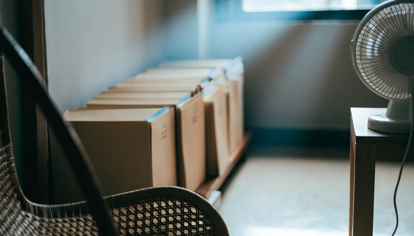 An empty reading desk by a window with paper trays and a fan of blank index cards